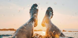 muzske nohy v mori pri zapade slnka
